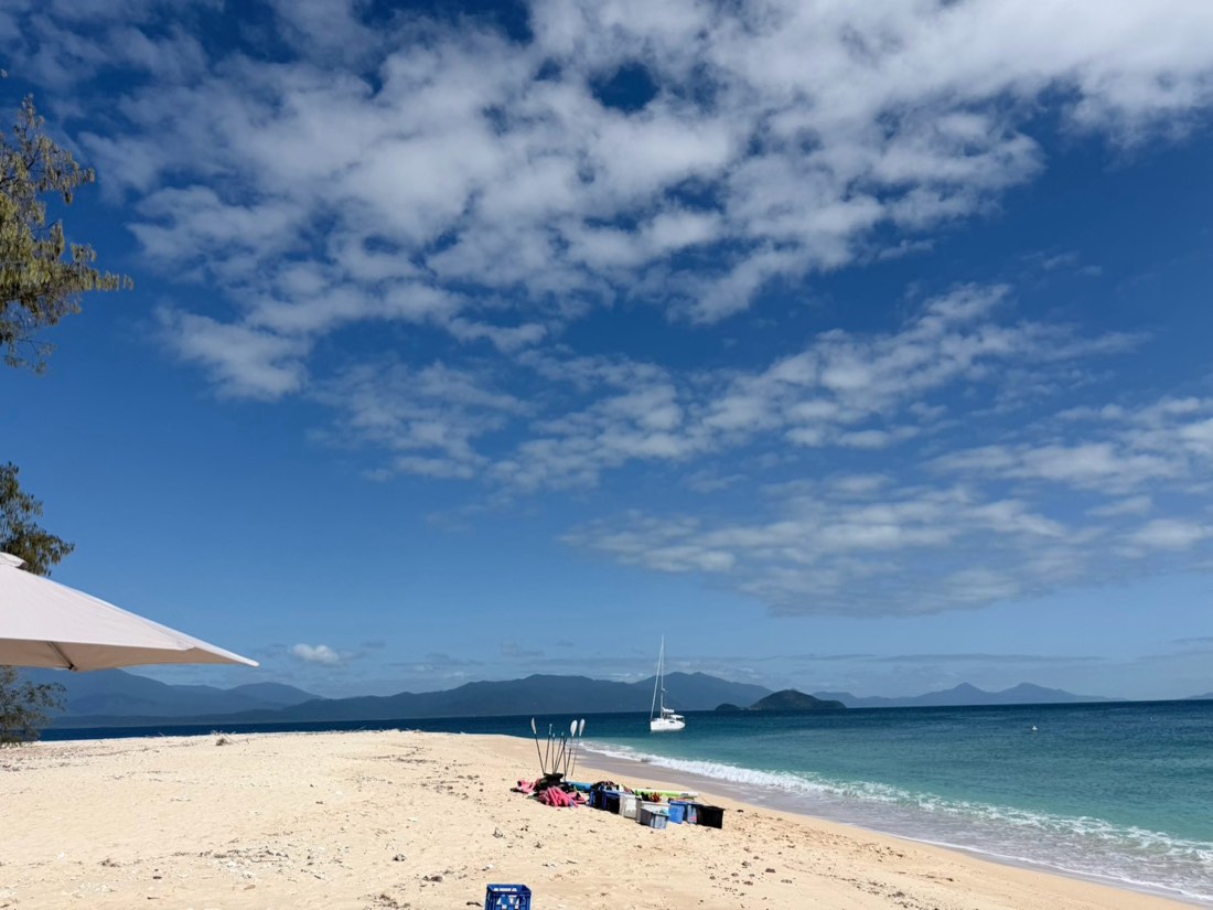 沖に船が浮かぶ島の白い砂浜