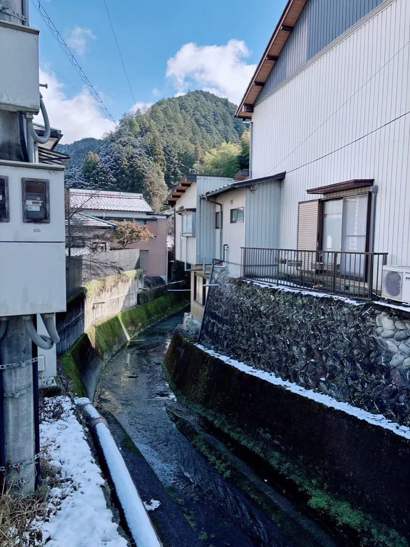 家と家のあいだを流れる水路と、岸に残る雪
